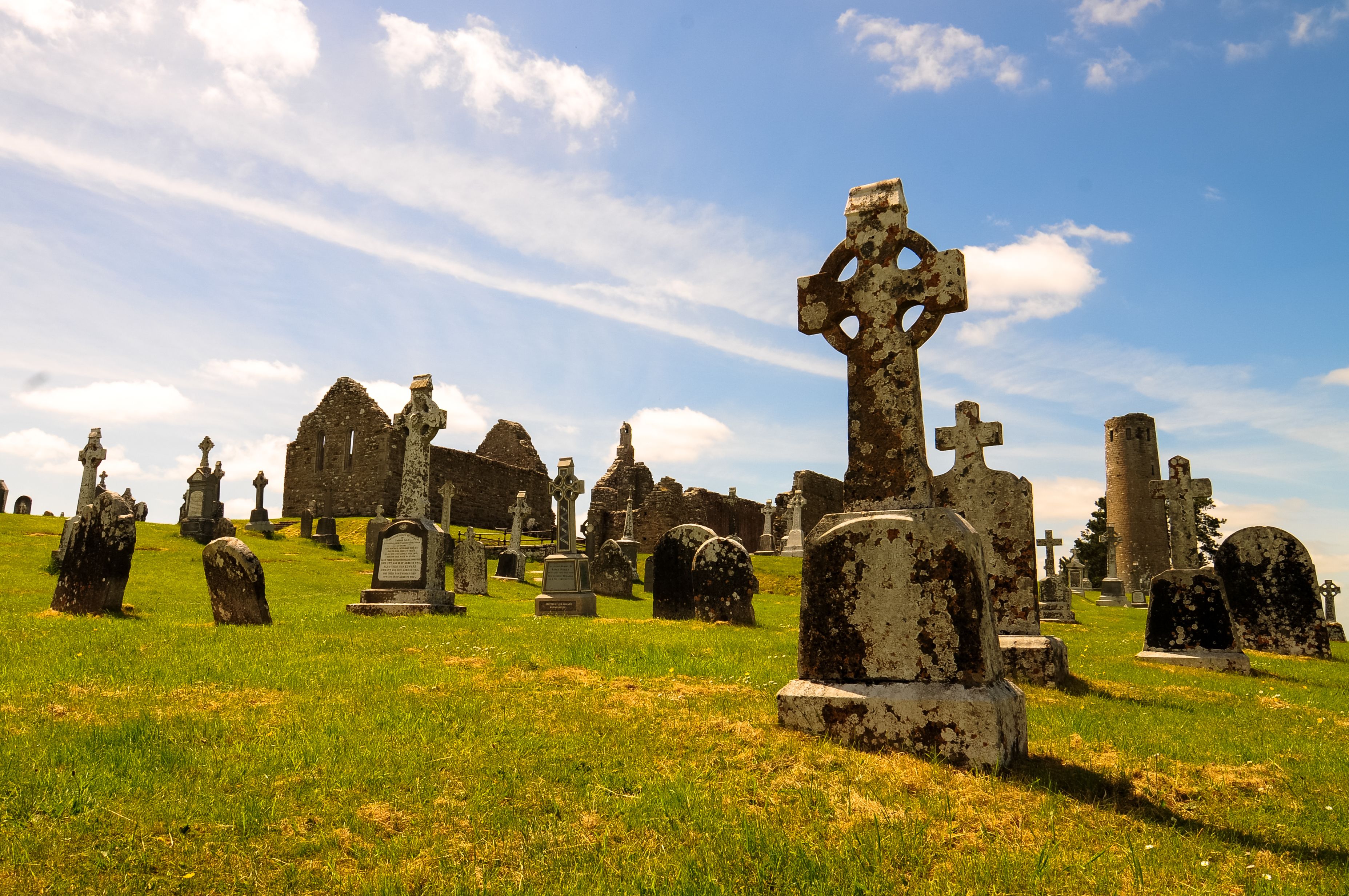 A cemetery with various gravestones and crosses, including a prominent Celtic cross in the foreground.