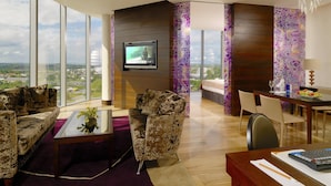 Un salón moderno con un televisor grande, asientos cómodos y vistas a la ciudad.