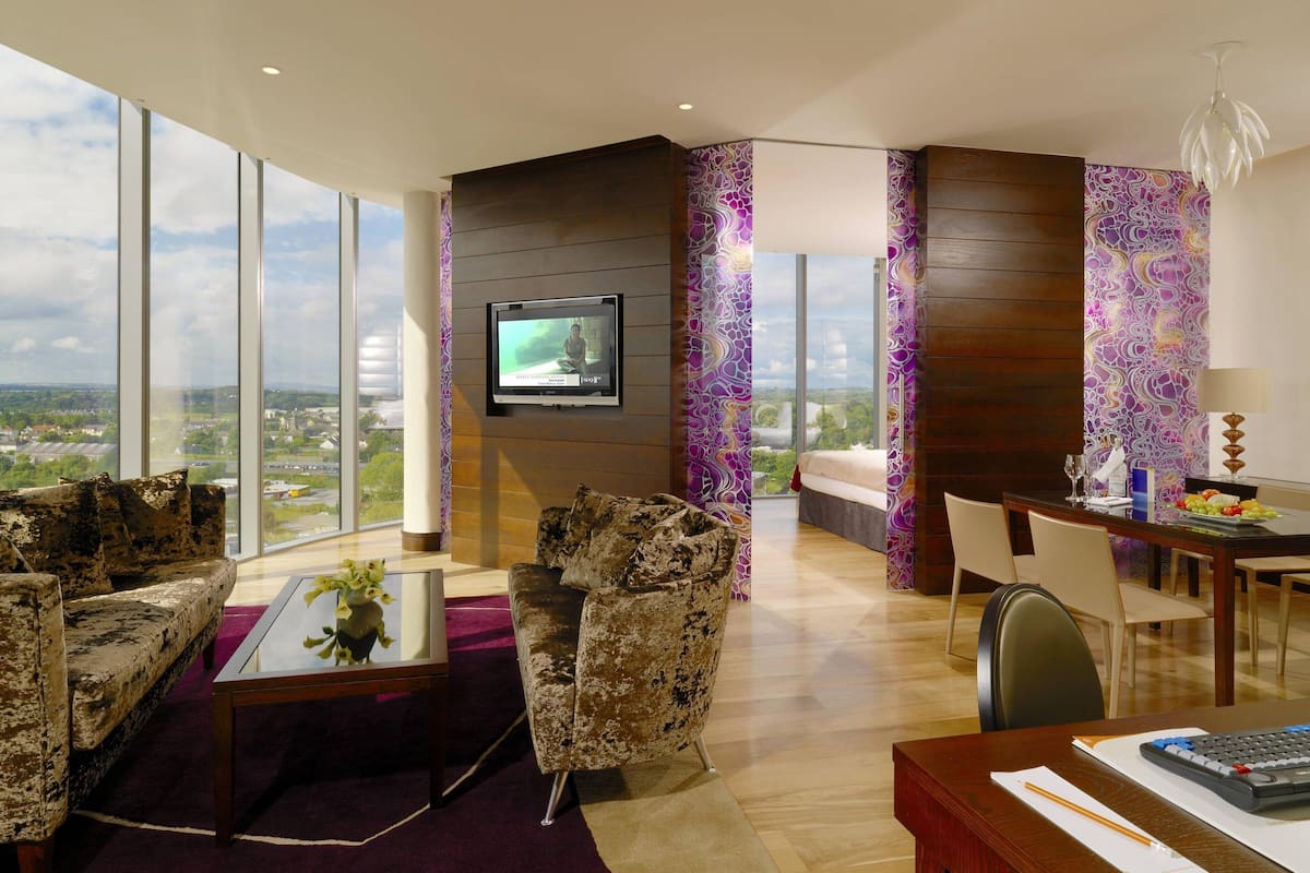 A modern living room with a large TV, comfortable seating, and a view of the city.