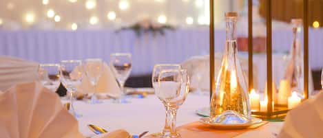 Una mesa dispuesta para un evento formal, con copas, platos y velas.