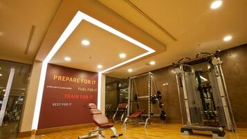 A gym with wooden flooring, exercise equipment, and motivational wall text.