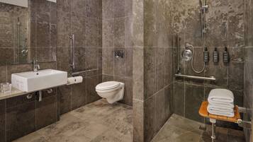 A modern bathroom with a sink, toilet, shower, and a towel rack.