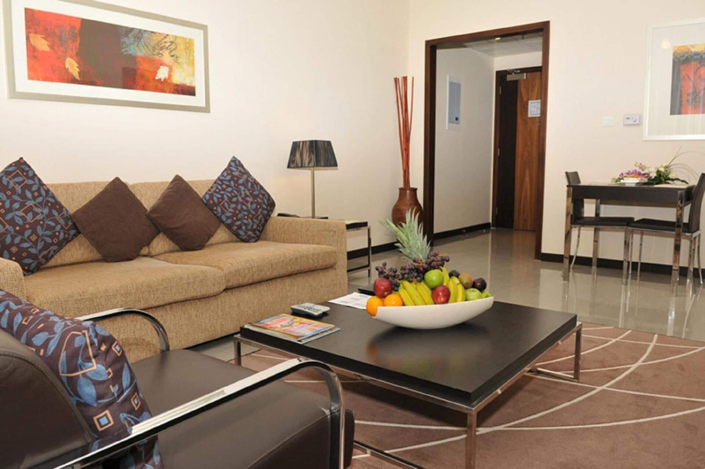 A modern living room with a sofa, coffee table, and a dining area with a table and chairs.