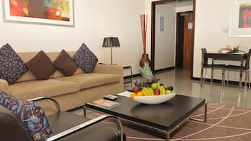 A modern living room with a sofa, coffee table, and a dining area with a table and chairs.
