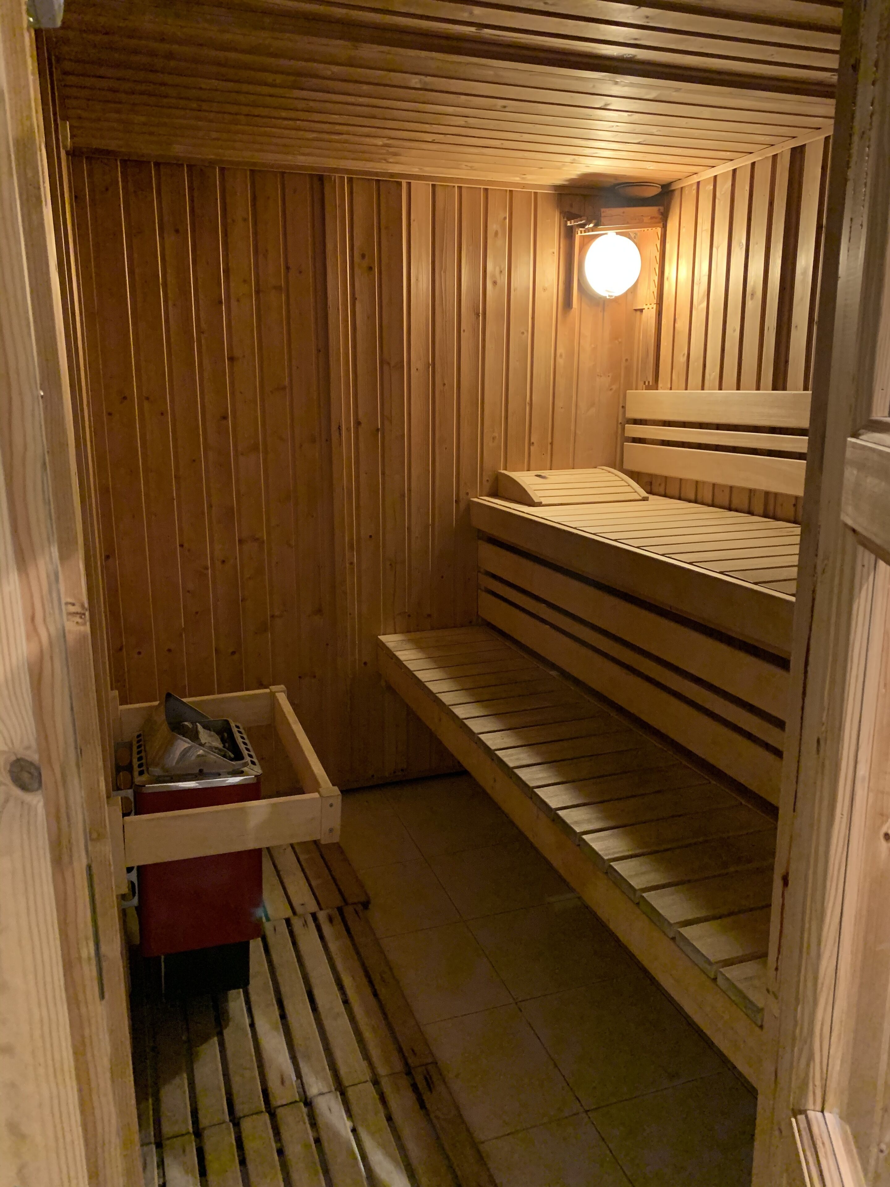A wooden sauna with benches and a small heater.