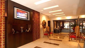 A hotel lobby with a reception desk, a television screen, and a seating area with ornate chairs. - The Eclipse Boutique Suites (Abu Dhabi)