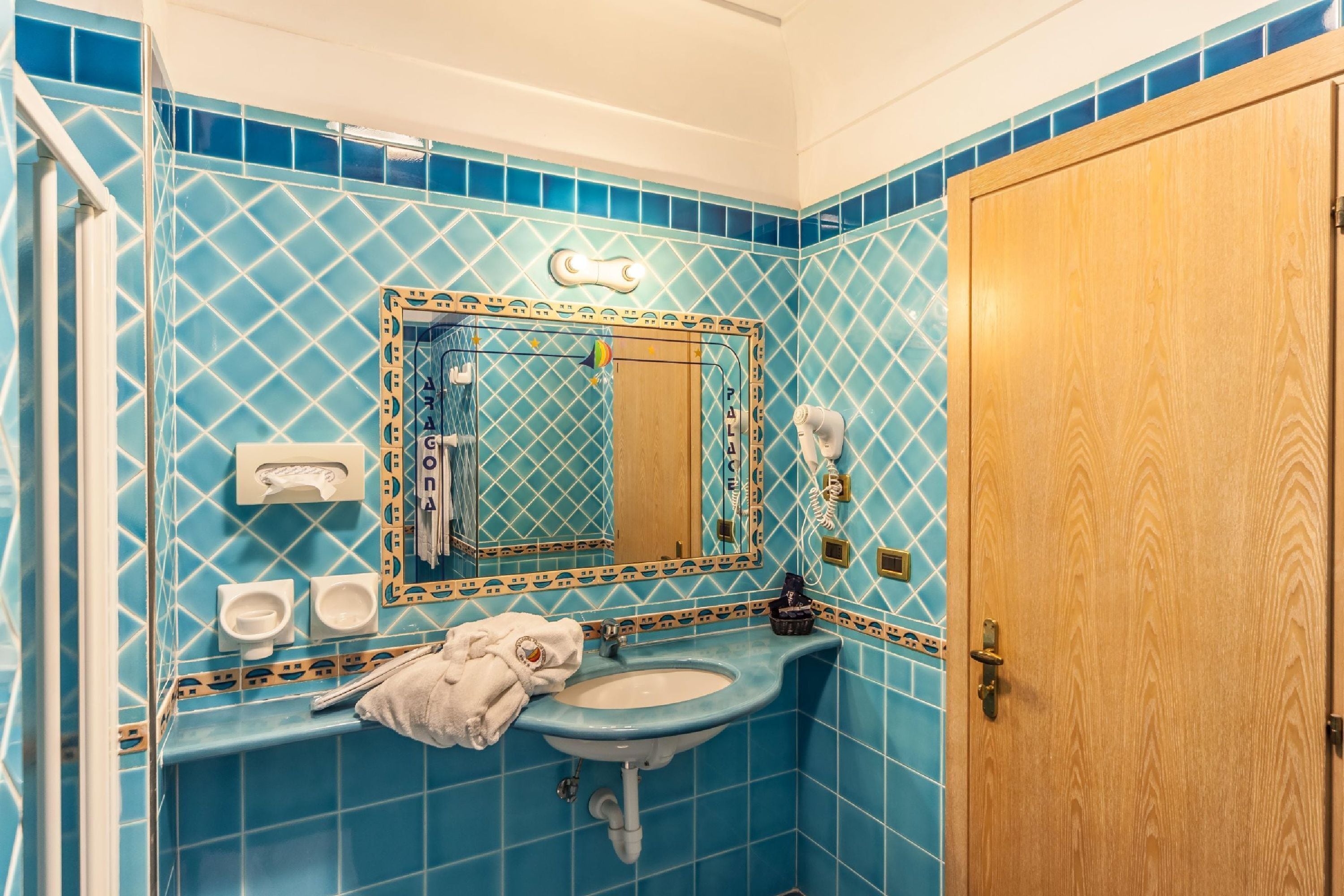 Ein Badezimmer mit Waschbecken, Spiegel, Handtuchhalter und einer Holztür.