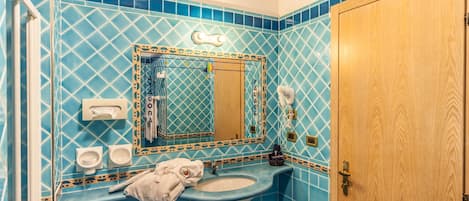 Ein Badezimmer mit Waschbecken, Spiegel, Handtuchhalter und einer Holztür.