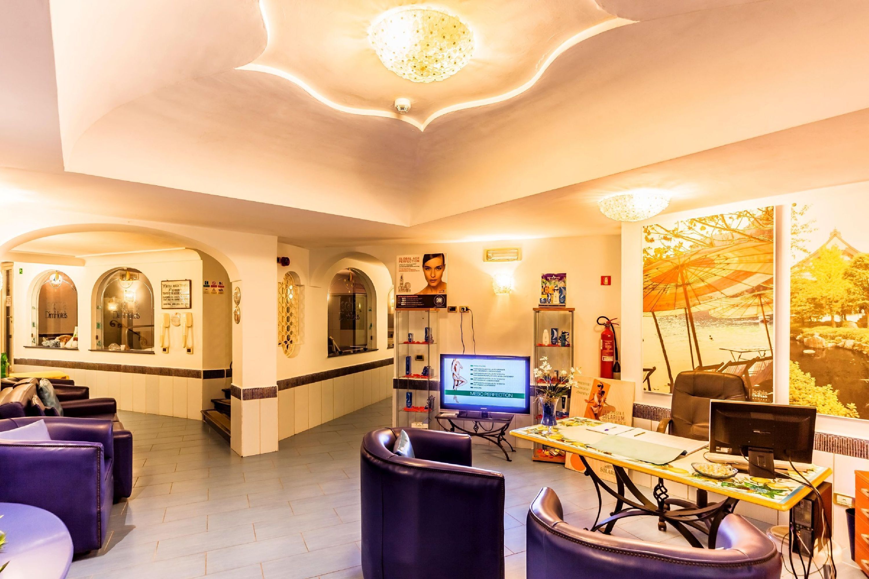 A hotel lobby with seating areas, a reception desk, a television, and a large window with a view.