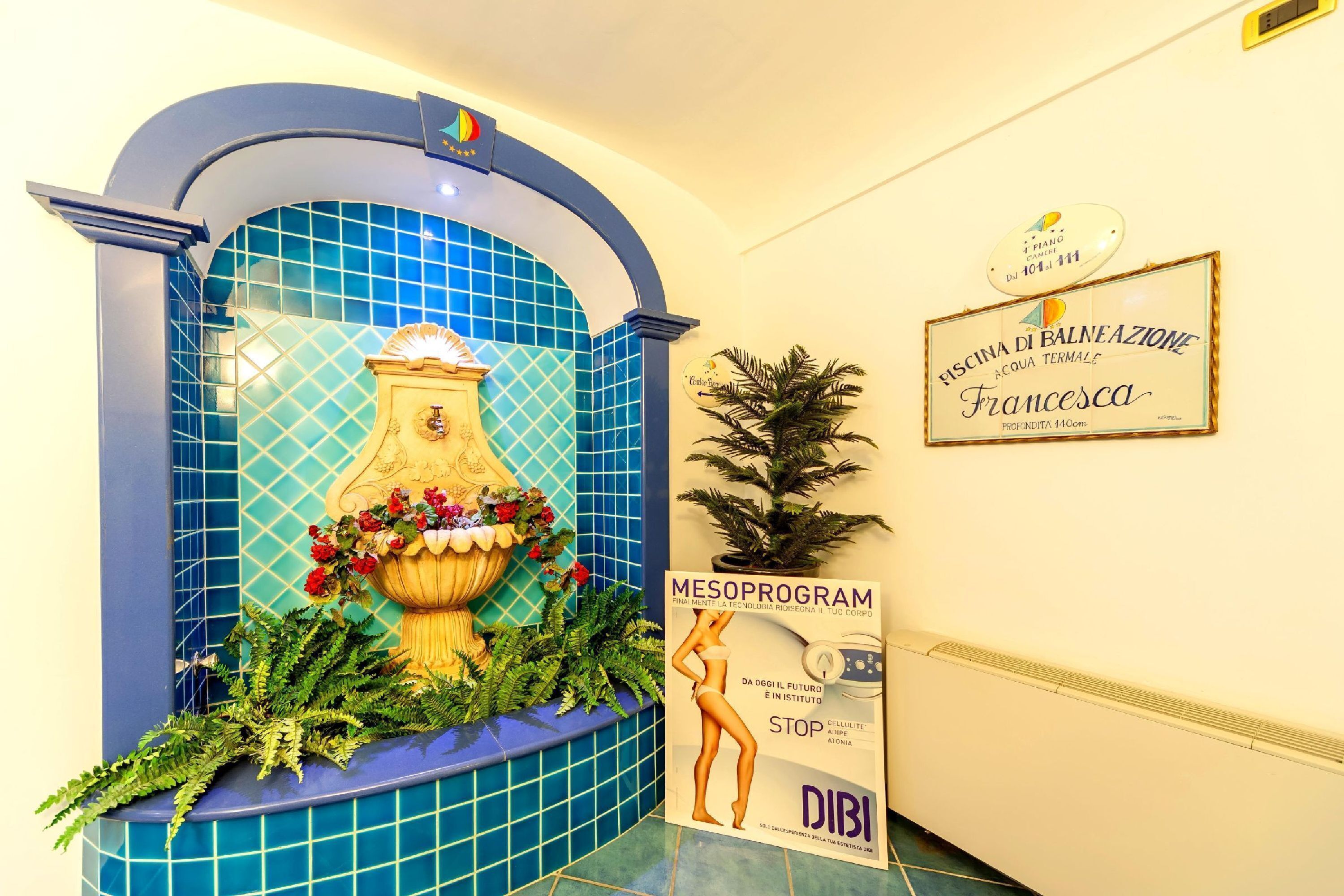 Una pared azul con azulejos, una fuente decorativa, un cartel enmarcado y un póster.