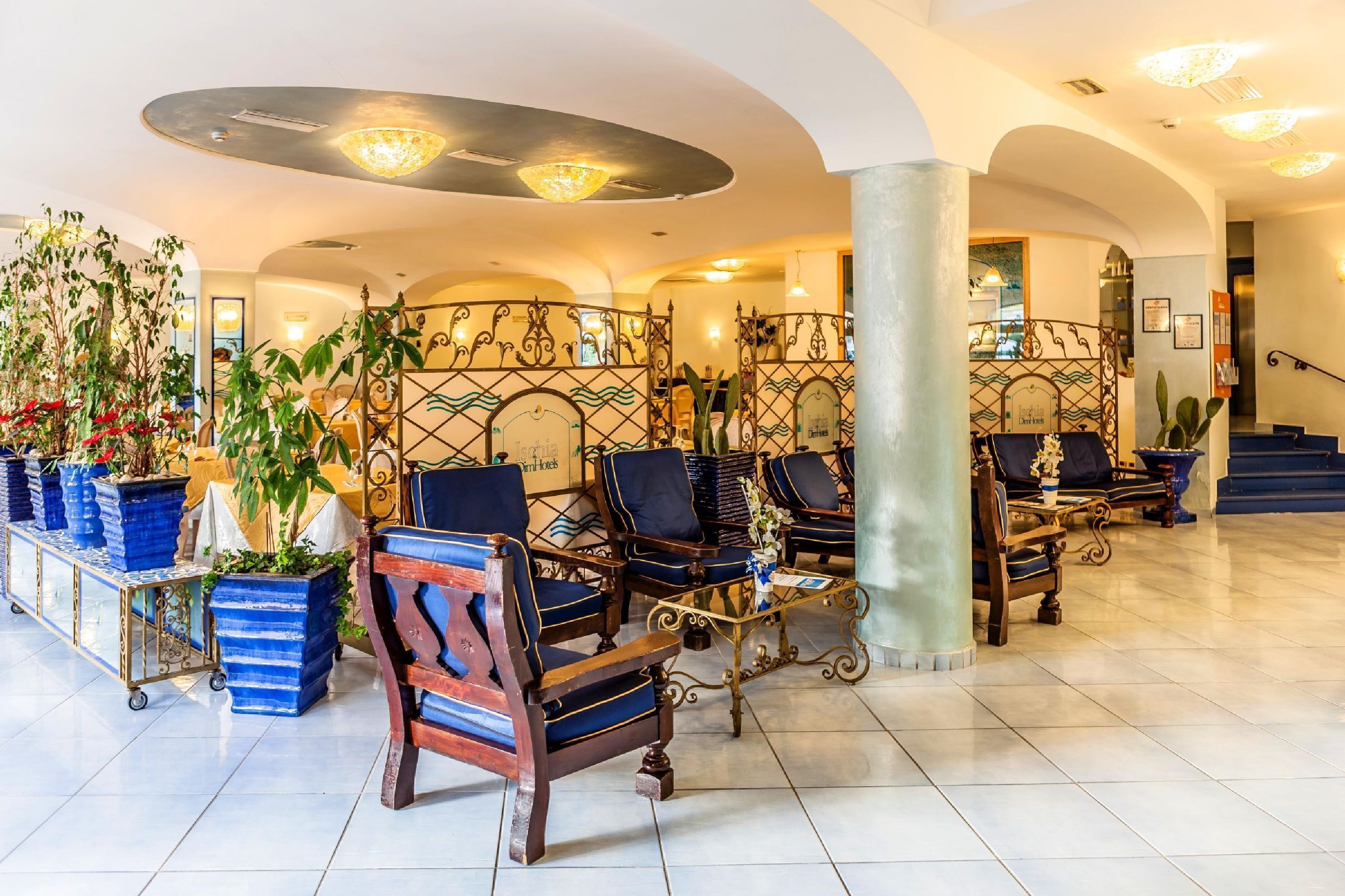 A hotel lobby with a seating area, potted plants, and a staircase.
