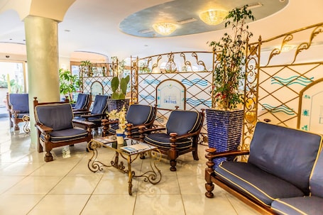 A lobby with ornate furniture, a reception desk, and a decorative wall with a wave pattern.. Aragona Palace Hotel & Spa