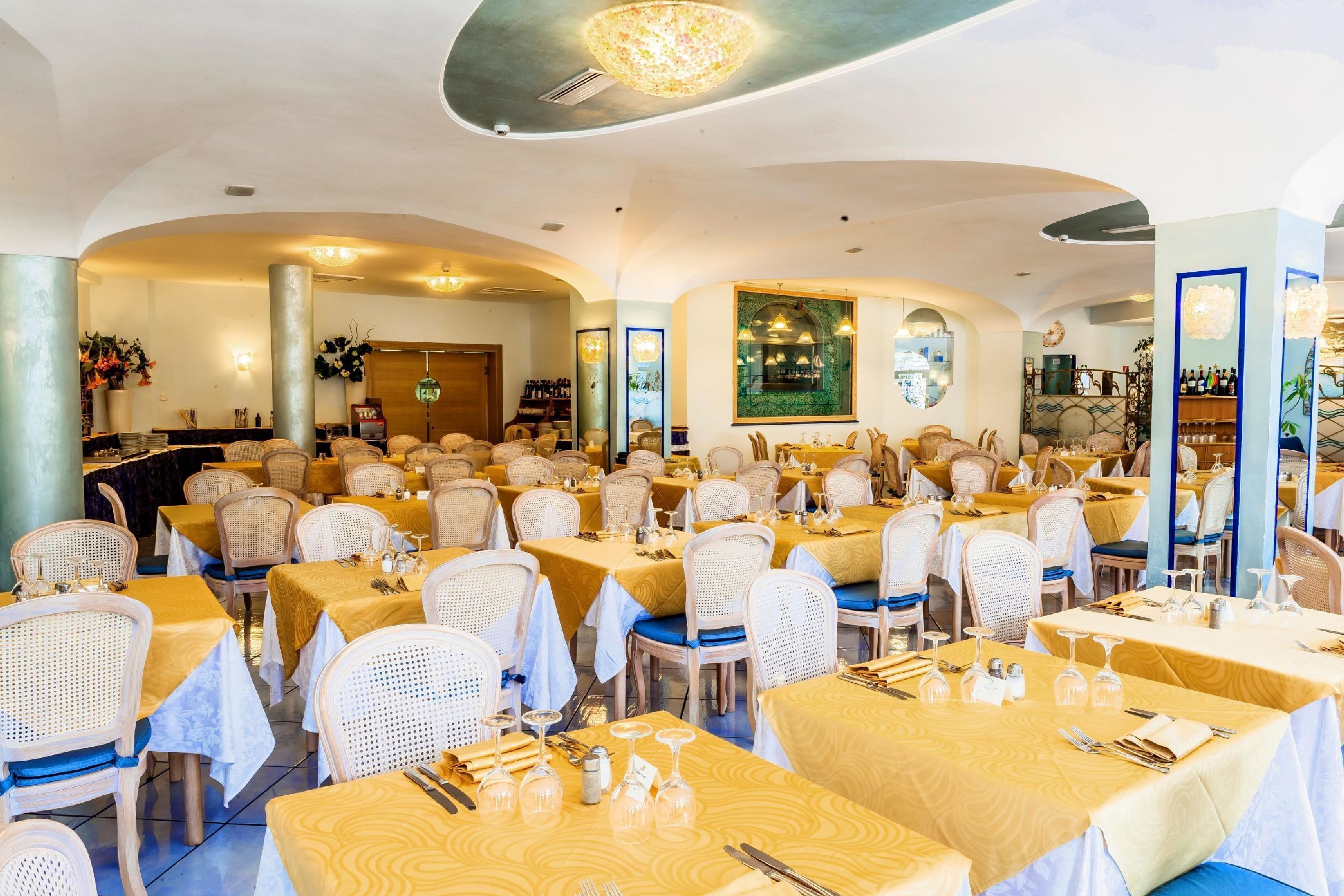 Un restaurante con varias mesas y sillas, una zona de bar y una pared decorativa.