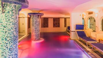 A spa area with mosaic columns, a pool, and lounge chairs.