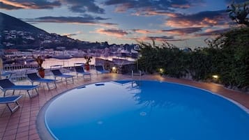 Una piscina techada, una piscina al aire libre, sombrillas