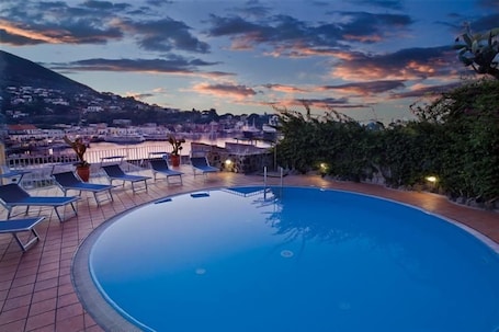 Una piscina techada, una piscina al aire libre, sombrillas