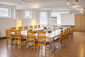 A conference room with wooden tables and chairs, a whiteboard, and a projector screen. - Hotel Kammweg (Grossbreitenbach)