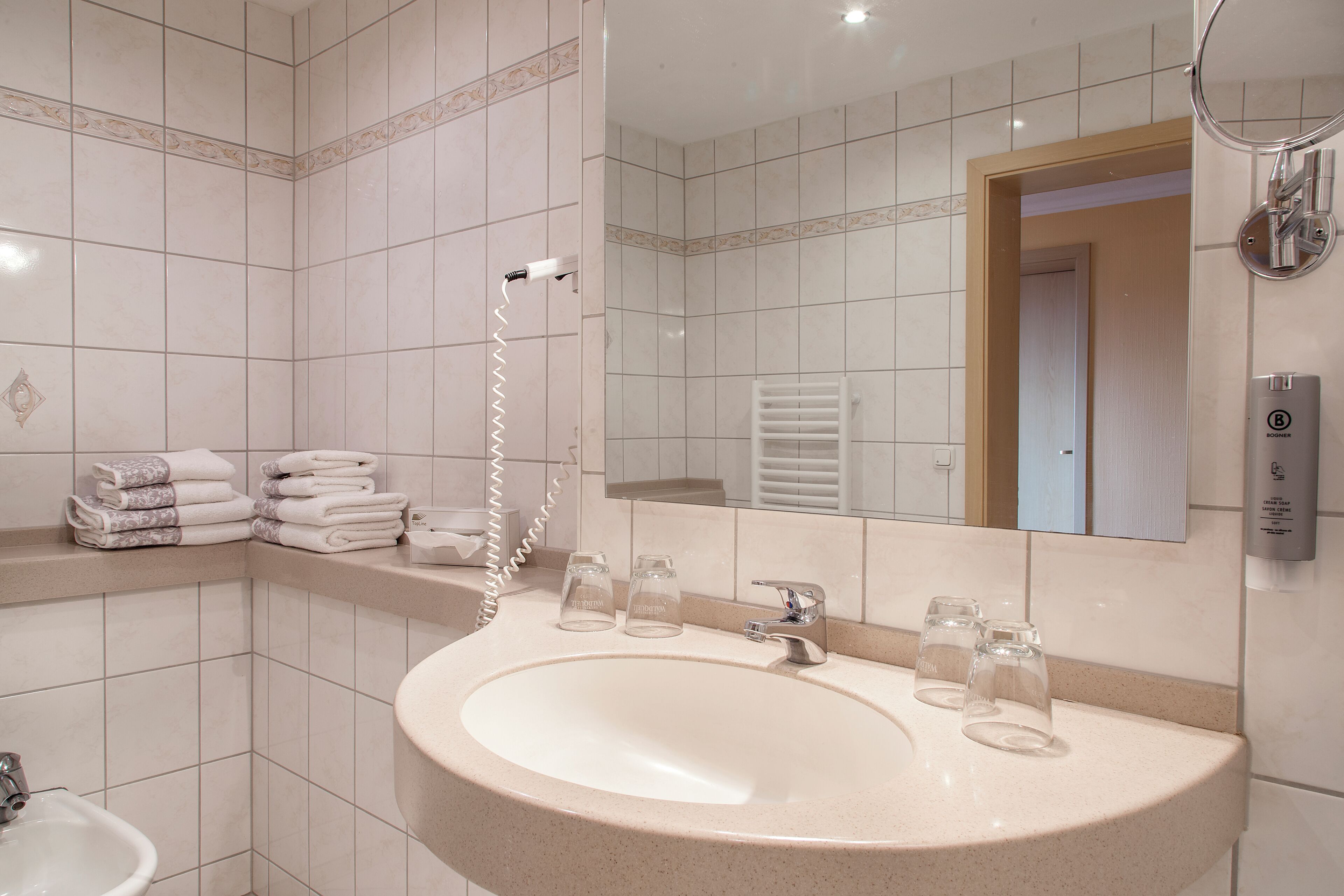 A bathroom with a sink, mirror, towel rack, and a shower.