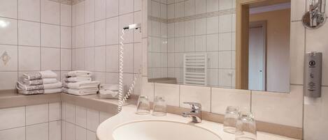 A bathroom with a sink, mirror, towel rack, and a shower.