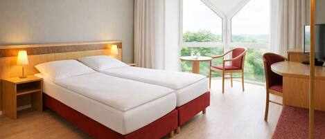A hotel room with a bed, bedside tables, a desk, a chair, and a TV.