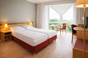 A hotel room with a bed, bedside tables, a desk, a chair, and a TV.