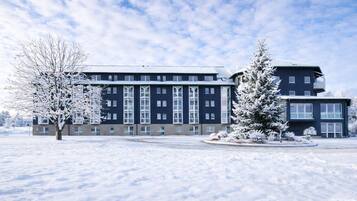 A multi-story hotel with a symmetrical facade, large windows, and a snow-covered landscape.