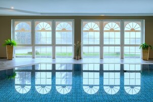 Una piscina interior amplia con vistas despejadas al exterior a través de grandes ventanales.