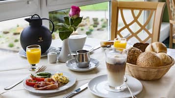 A breakfast setting with a table set for two, including plates of food, a pitcher, a cup, and a basket of bread.