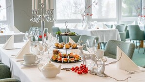 A dining table set with a tiered dessert display, white teapot, and decorative candles.