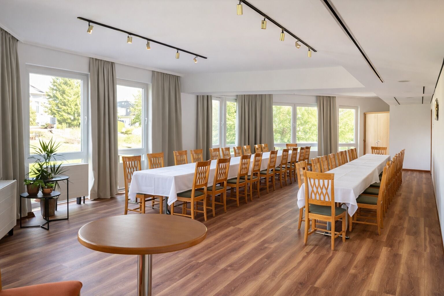 A conference room with a long table, multiple chairs, and a small round table.