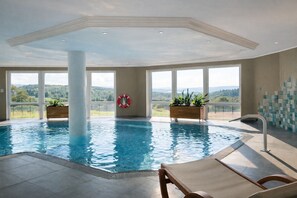 An indoor swimming pool with clear views of the outdoors, large windows, and a lifebuoy on the wall. - Hotel Kammweg (Grossbreitenbach)