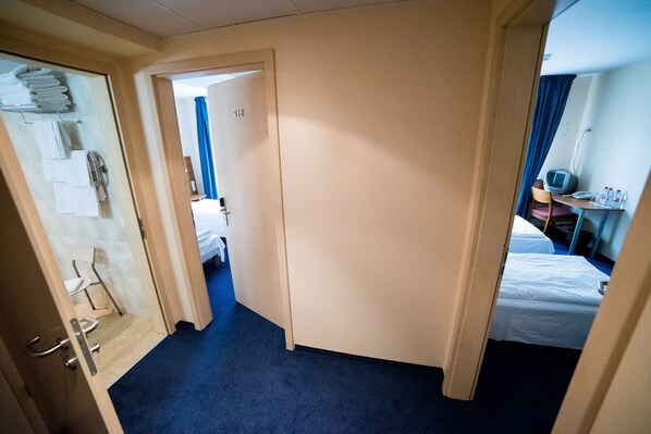 A hotel room with a bed, a desk with a computer, and a bathroom with towels and a shower. - Hotel Tigra (Priekuli)