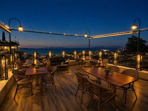 An outdoor terrace with wooden flooring, wicker furniture, and string lights. - GLK PREMIER Regency Suites & Spa - Special Class (Istanbul)