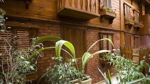 Un bâtiment en bois avec des murs en briques, des volets en bois et des plantes en pot.