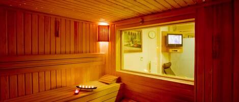 A sauna room with wooden benches, a television, and a window.