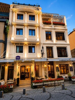Un hotel con una entrada destacada, un letrero que indica Premier Emergency Suites y un restaurante visible llamado Garden Restaurant.