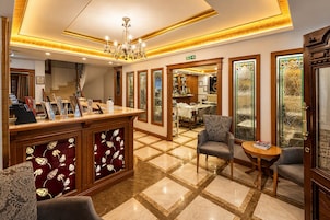 Un vestíbulo de hotel con mostrador de recepción, zona de estar y vista al comedor.