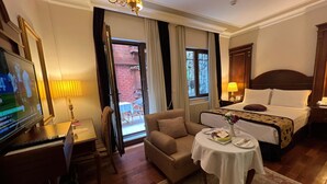 Une chambre d’hôtel avec un lit, un bureau avec une télévision, une chaise, une table avec un vase et une vue sur l’extérieur.