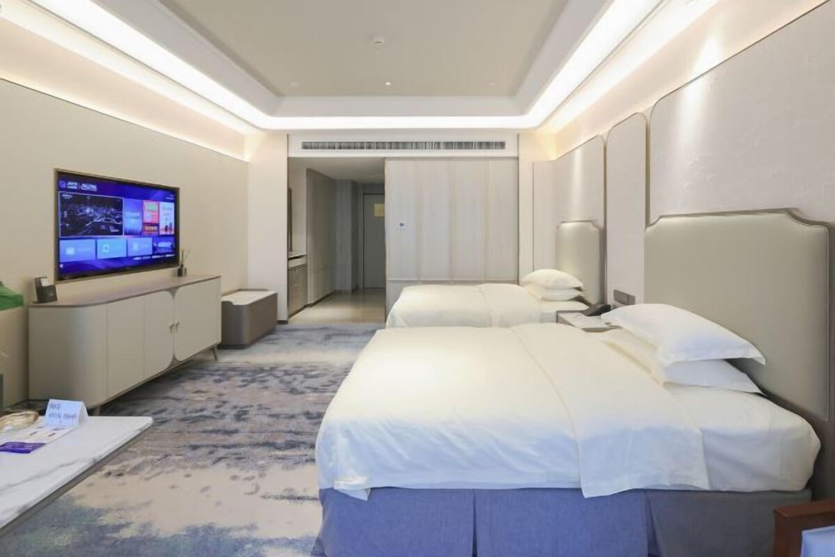 A hotel room with two beds, a flat-screen TV, a desk, and a walk-in closet.