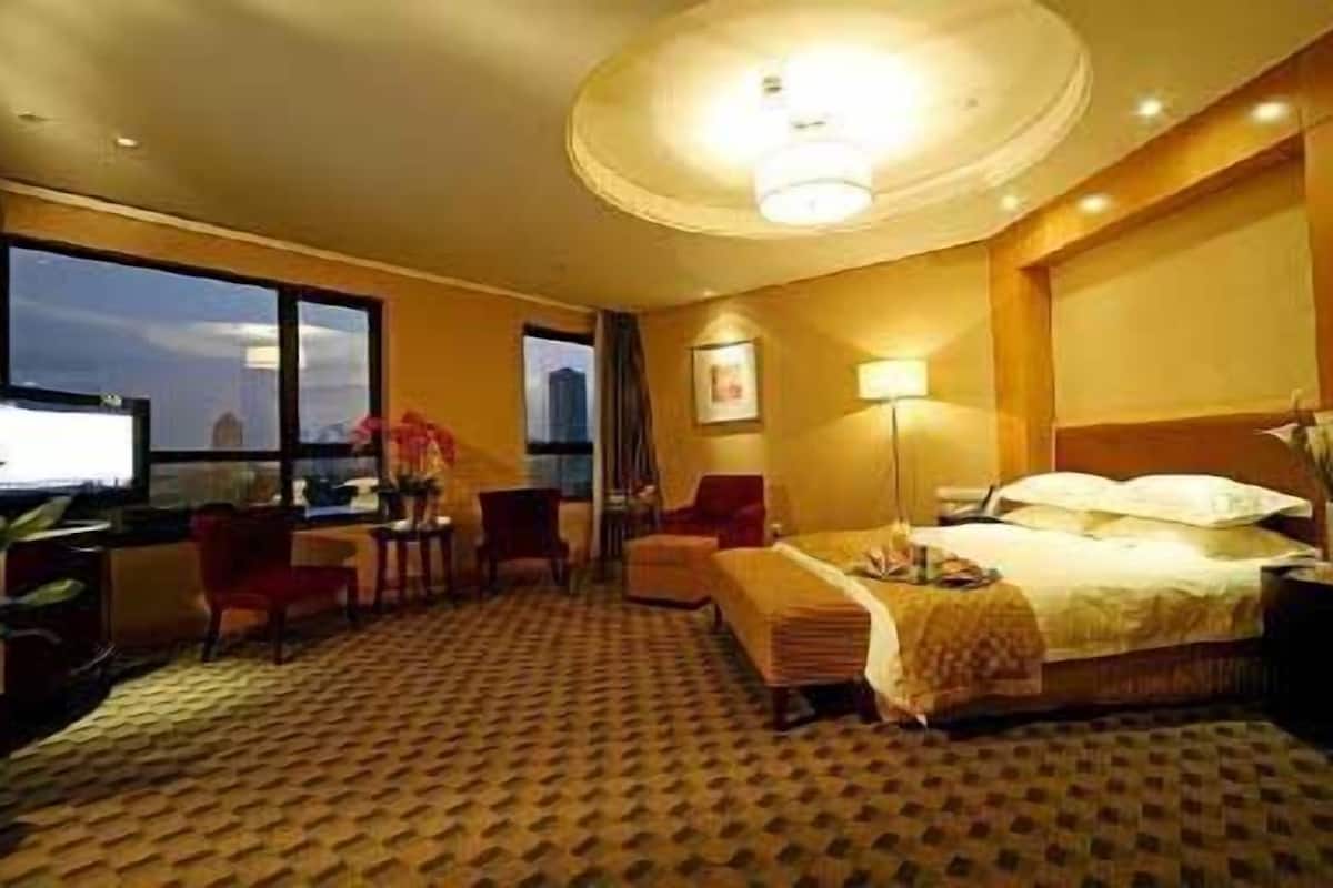 Une chambre d’hôtel avec un lit, un bureau avec un ordinateur, une chaise, une lampe et une fenêtre donnant sur un paysage.