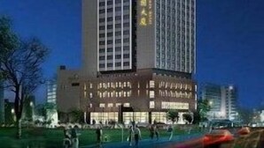 Un edificio alto y moderno con una entrada destacada y señalización iluminada.
