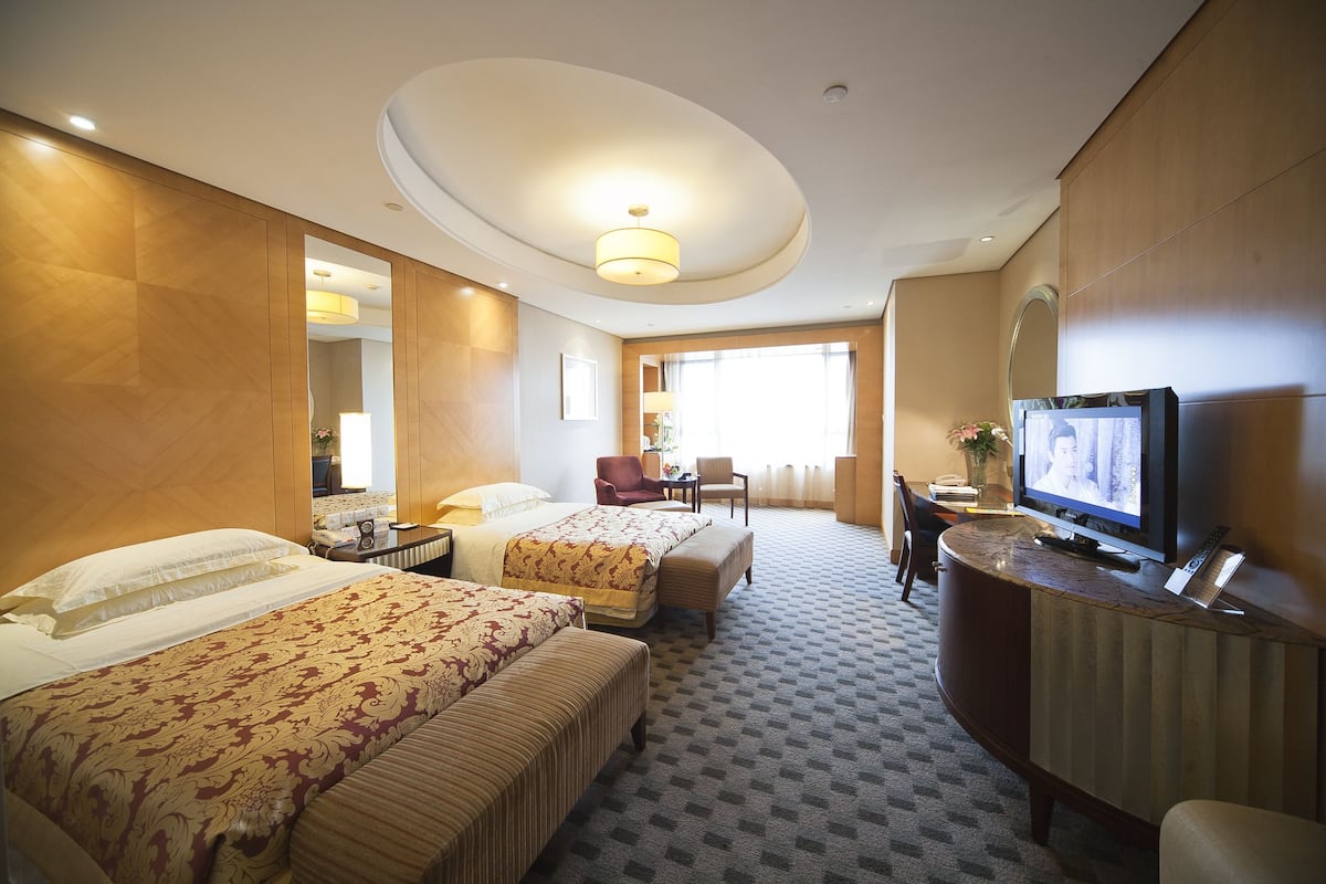 Une chambre d’hôtel avec deux lits, une télévision, un bureau et une chaise.
