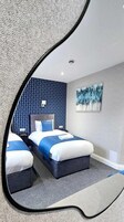 A modern hotel room with a large bed, two bedside tables, and a painting on the wall.