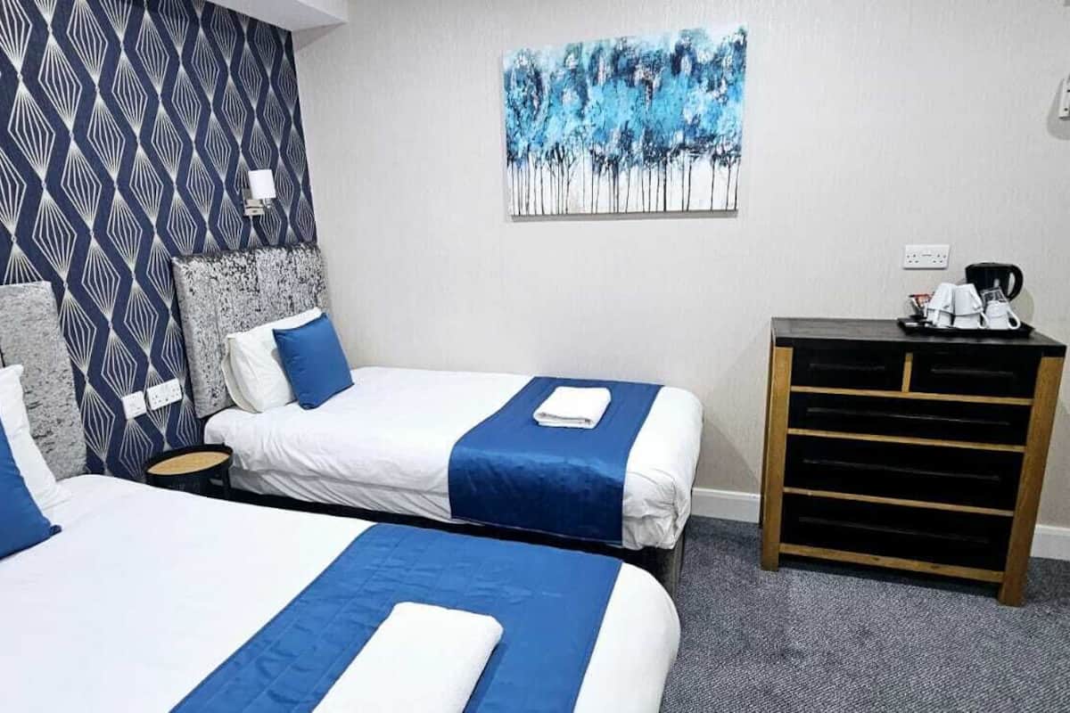 Una habitació d'hotel amb dos llits, un escriptori petit, un quadre i una paret amb dibuixos.