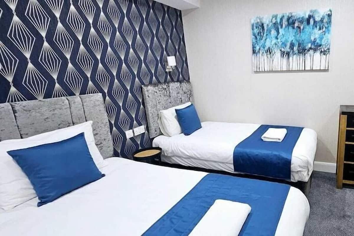 Habitació d'hotel amb dos llits, una taula petita, un quadre a la paret i una prestatgeria de pared.