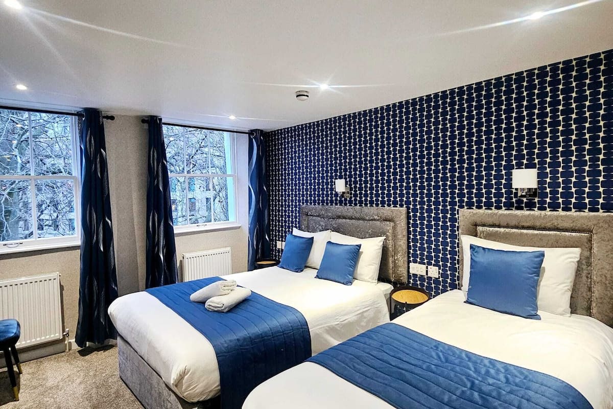 Habitació d'hotel amb dos llits, un finestral gran i un mur amb dibuixos.