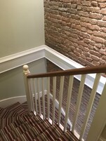 A staircase with a wooden handrail and striped carpet.