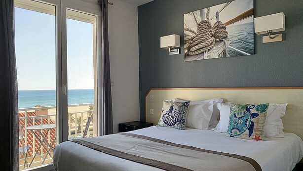 A hotel room with a large bed, a view of the sea, and a painting on the wall. - Le Regina (Canet-en-Roussillon)