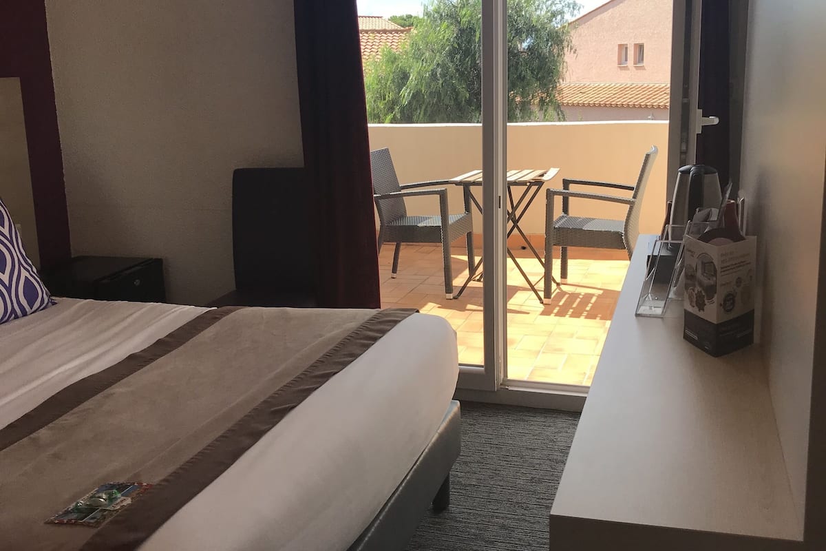 Una habitación de hotel con cama, escritorio y vistas al balcón exterior.