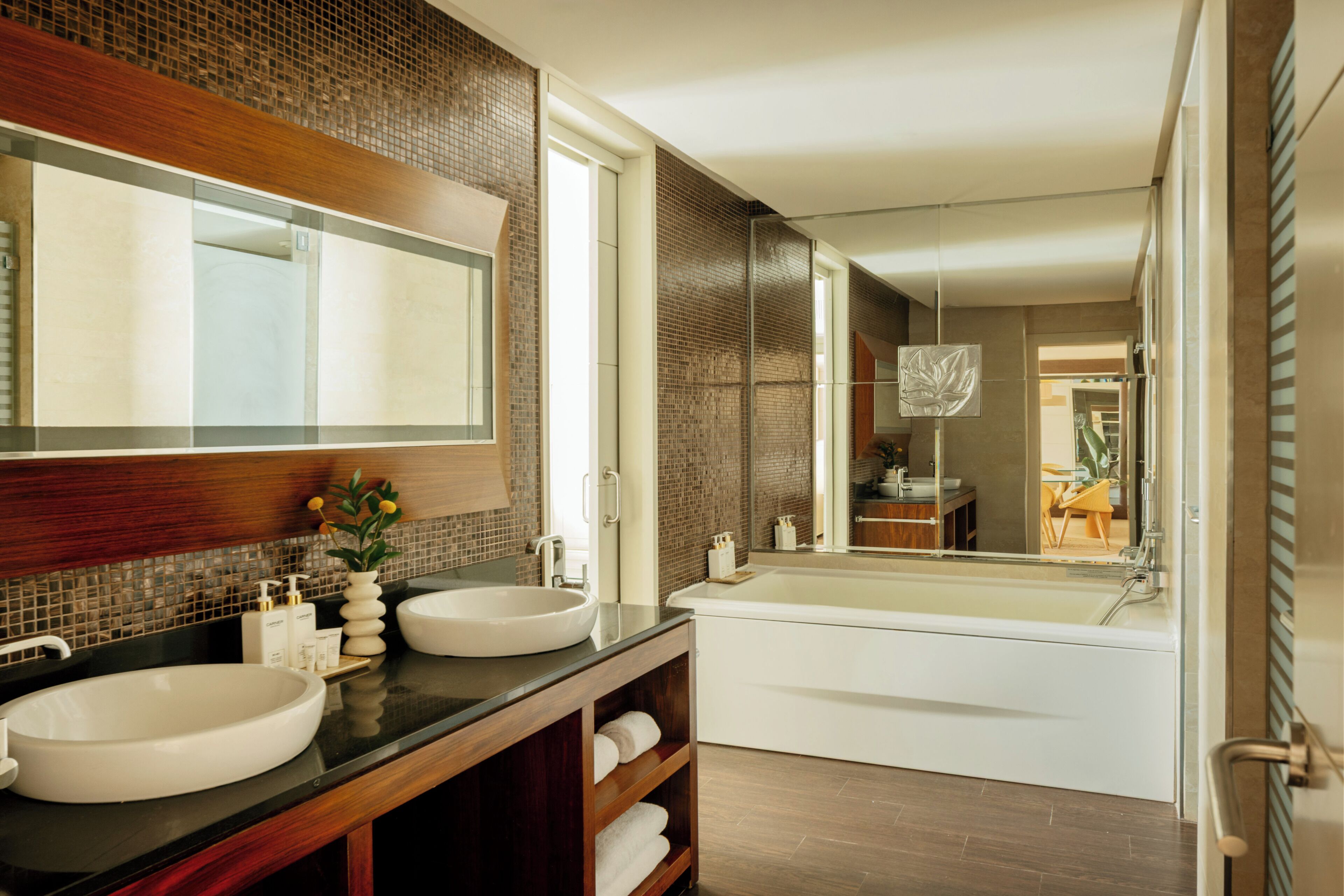 A modern bathroom with two sinks, a large mirror, and a bathtub.